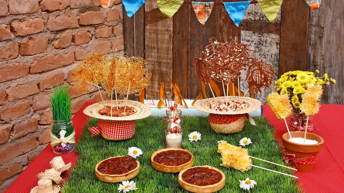Mesa de festa junina com doces, bandeirinhas e flores
