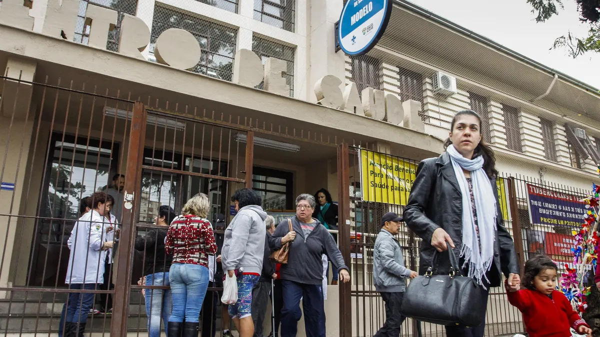 Fila na porta de um centro de saúde em Porto Alegre, com adultos, idosos e uma criança