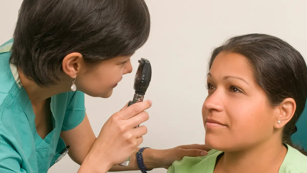 Profissional de saúde examinando os olhos de uma paciente com um aparelho de luz